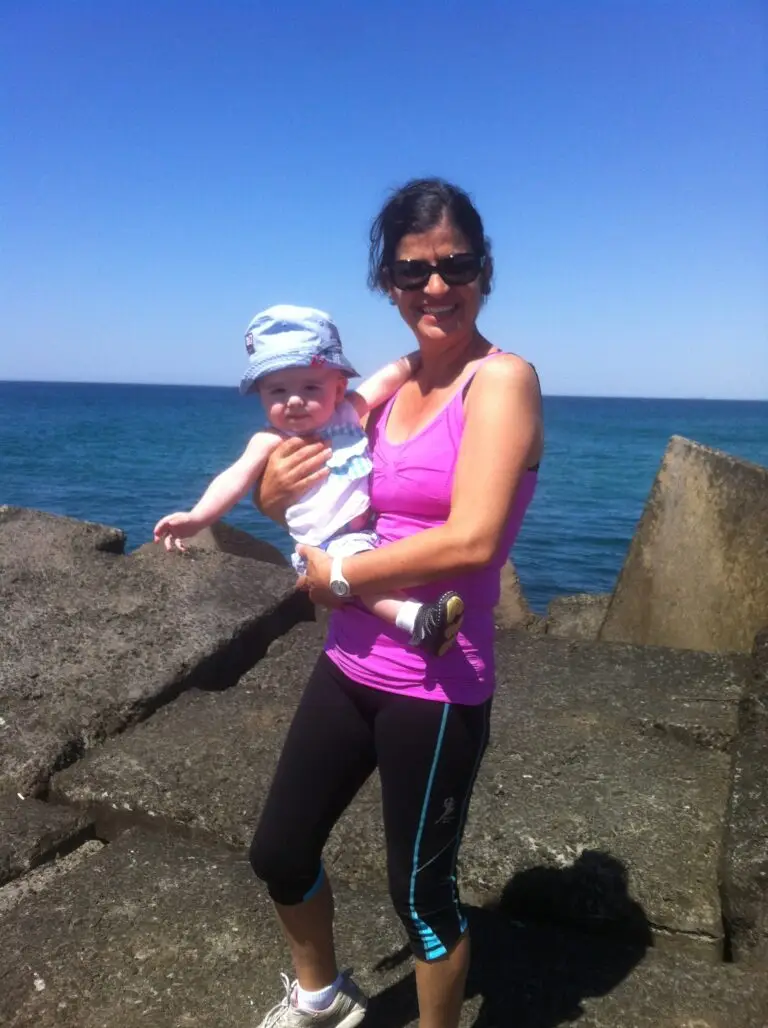 Carmela standing at beach holding grandson, Hunter.